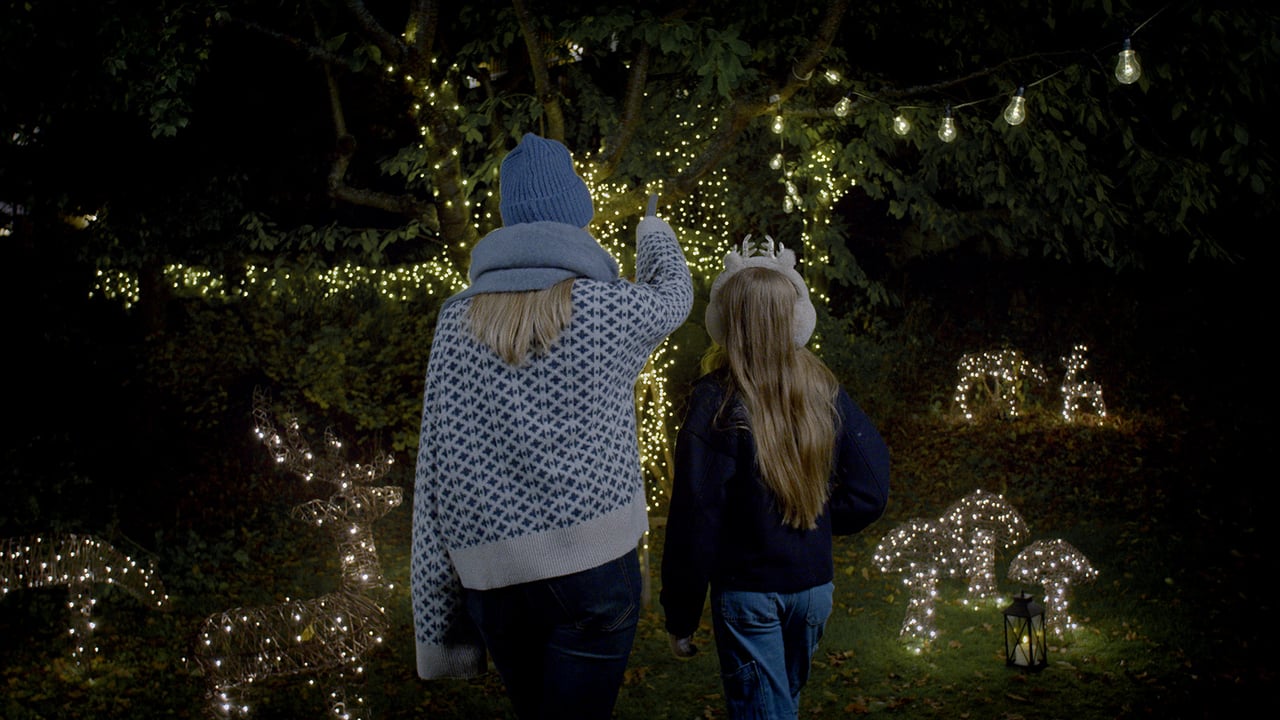 Zwei Personen im Garten bestaunen Lichtdekorationen und Bäume mit Lichterketten.