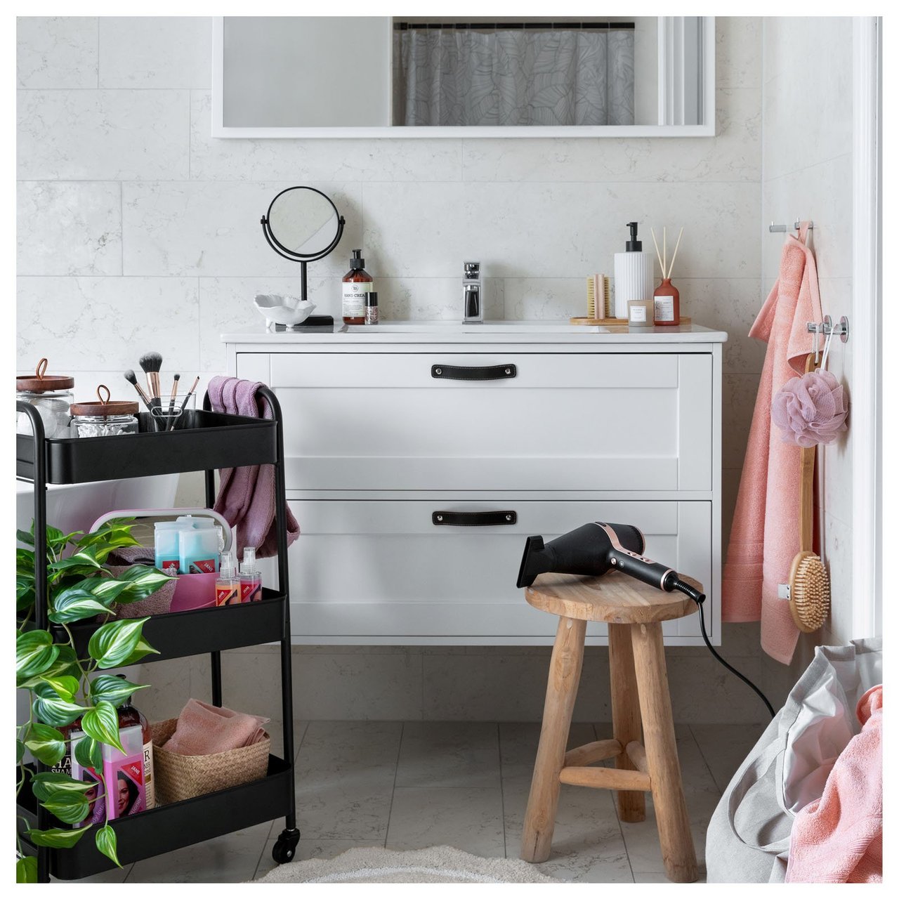 Kylpyhuone, jossa on peili, säilytysvaunu, muotoilutuotteita, pyyhekoukut ja puinen jakkara, jolla on hiustenkuivaaja.