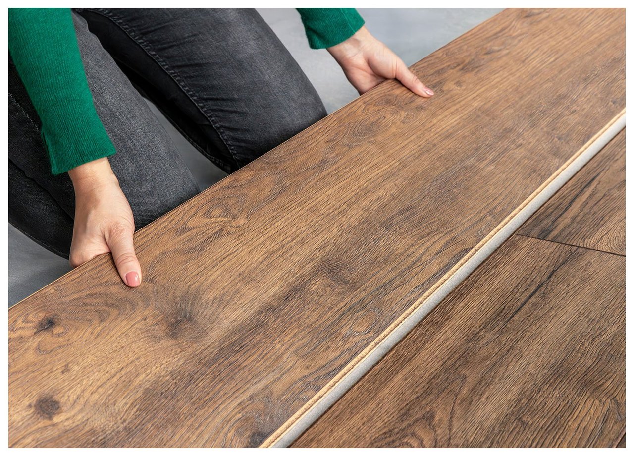 Närbild på person som lägger laminatgolv i ekfärgat trä.