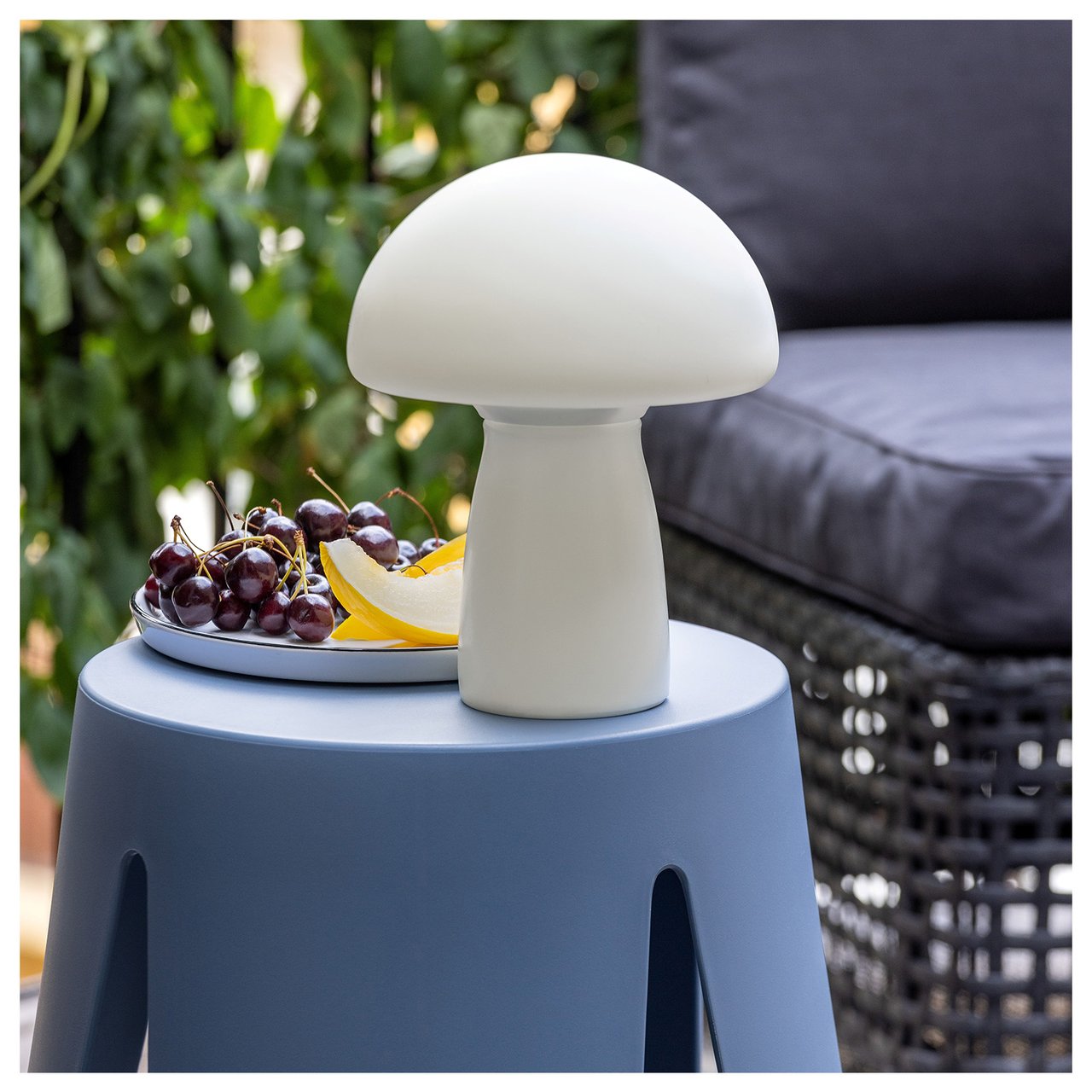 En liten hvit soppformet solcellelampe står på en blå krakk.