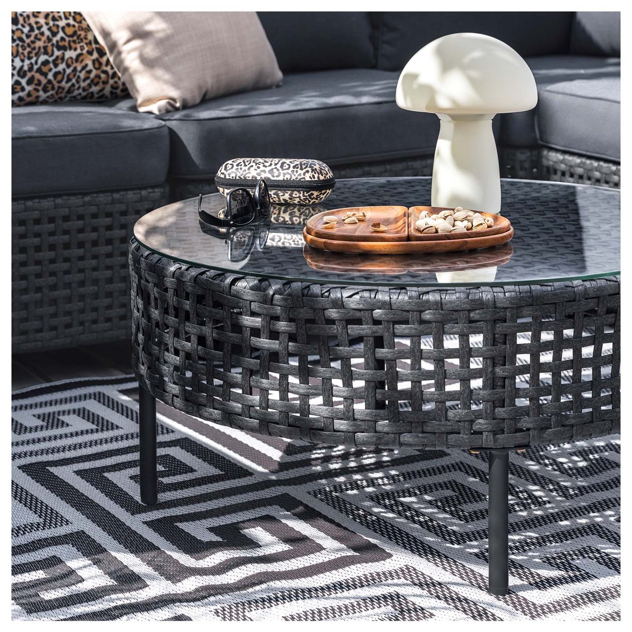 Svart sofabord på et uteteppe med svart-hvitt, grafisk mønster.