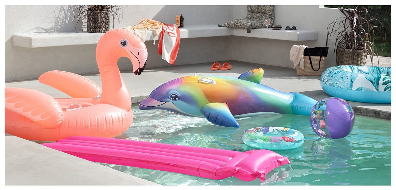 Utendørs basseng der oppblåsbare vannleker i form av en flamingo og delfin flyter.