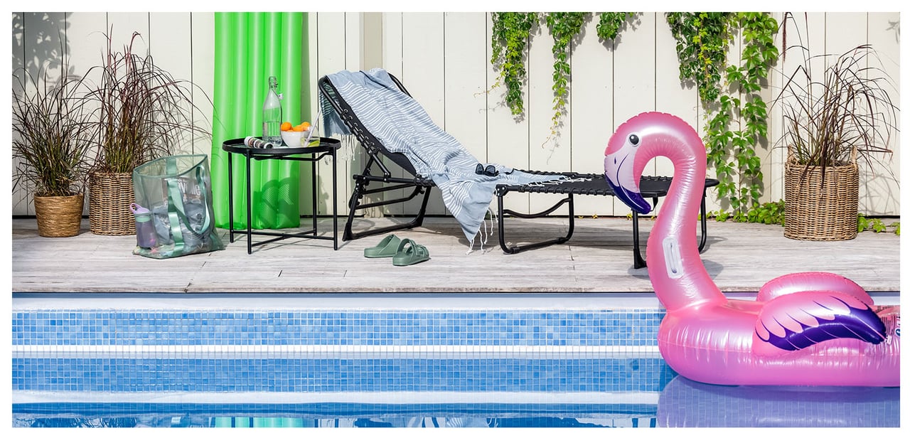 Uima-allasalue, jossa on aurinkotuoleja, uimaleluja ja puhallettava flamingo vedessä.