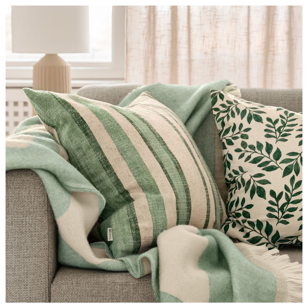 Grüne Kissen auf einem grauen Sofa.