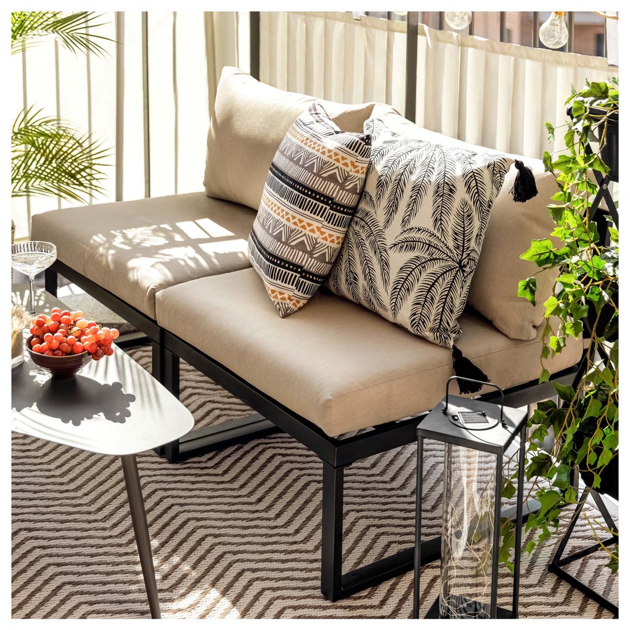 Ein sonniger Balkon mit einem Lounge-Sofa mit Polsterauflagen und Outdoor-Kissen.