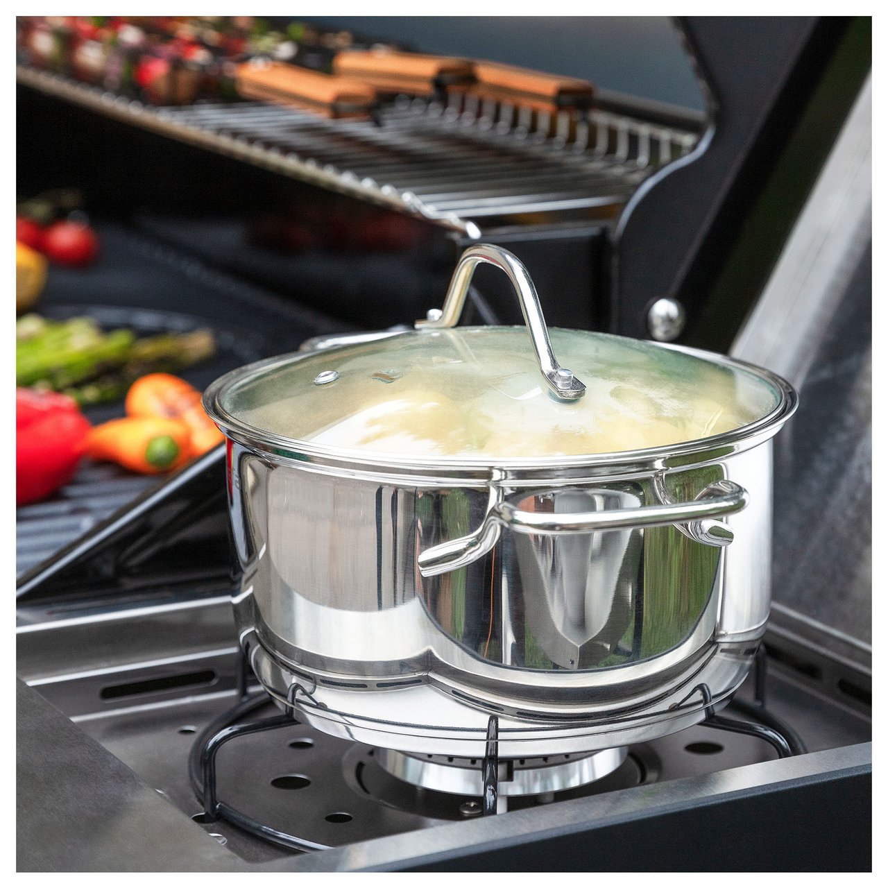 Närbild på en kastrull som står på en gasolgrillhäll.