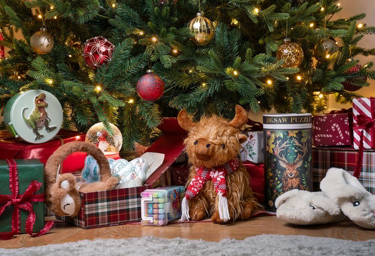 Gaver og leker ligger under et pyntet juletre klart for jul.