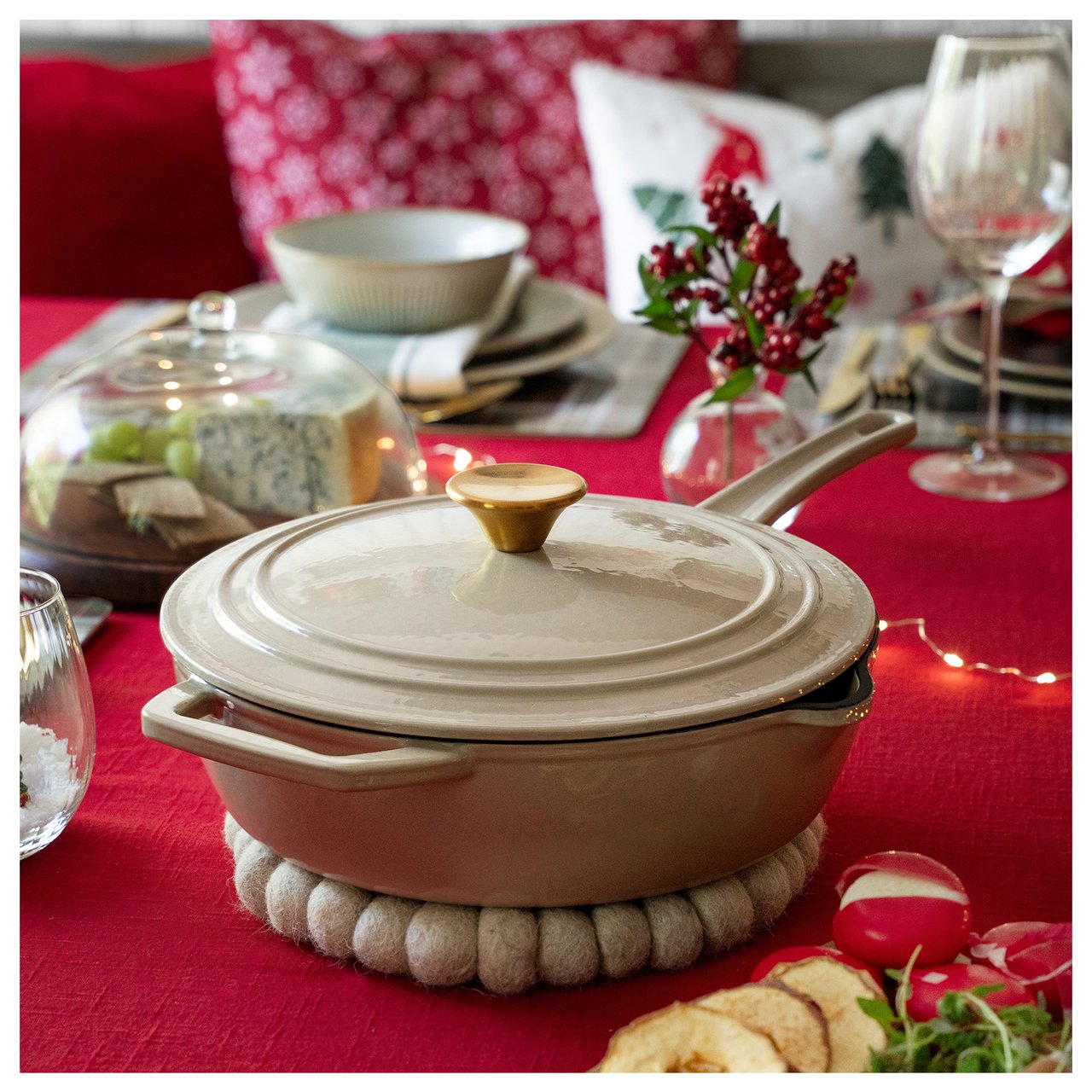 Weihnachtstisch mit roter Decke und beigem Gusseisentopf.