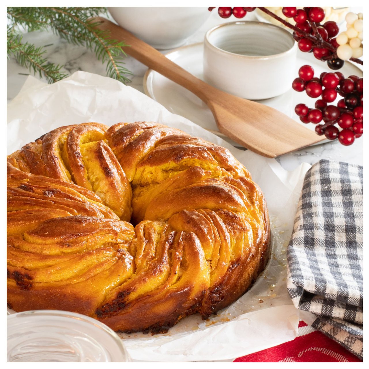 Nygräddad saffranskrans på bakplåtspapper omgiven av köksredskap och juldekorationer.