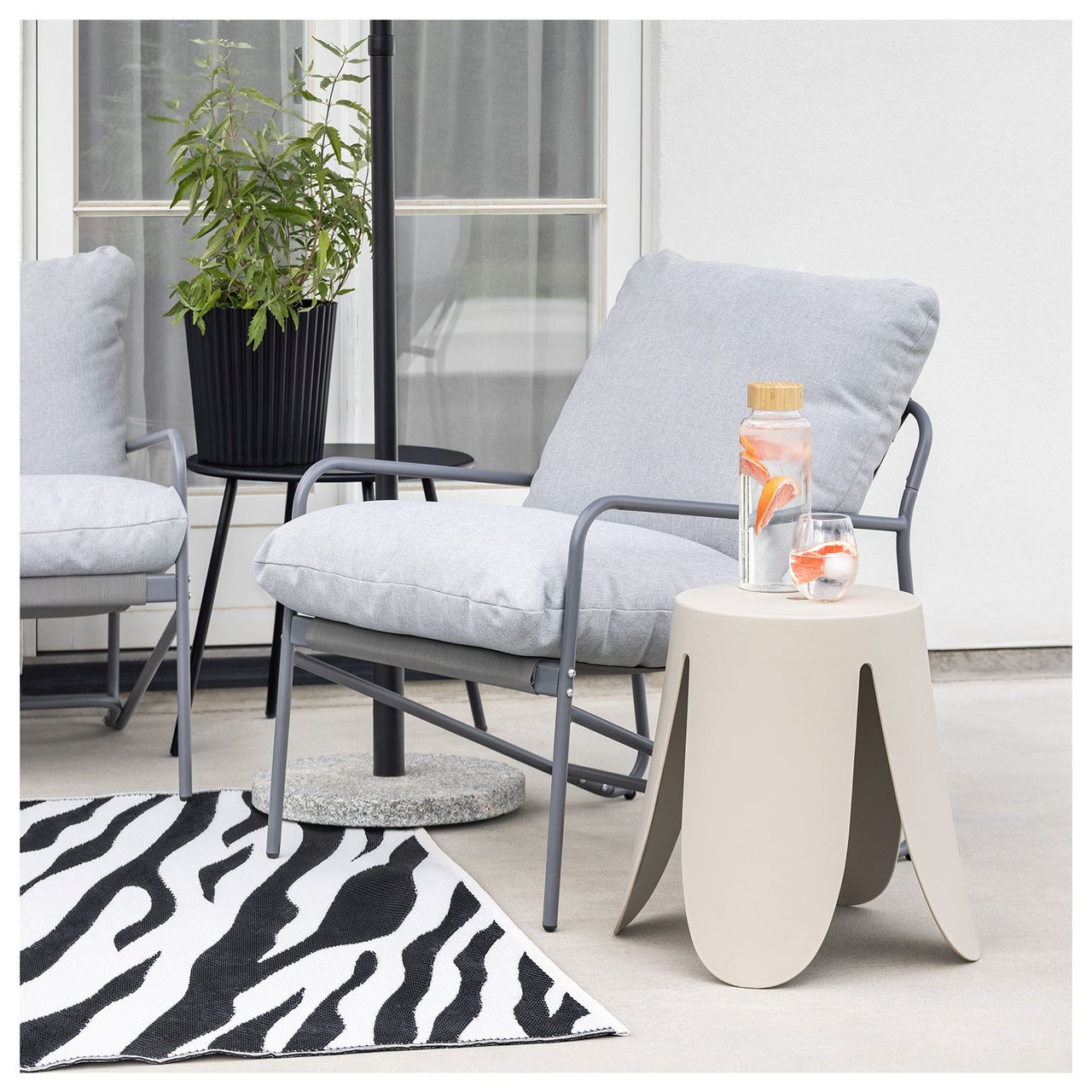 En sofagruppe i stål med grå puter på et teppe med sebrastriper.