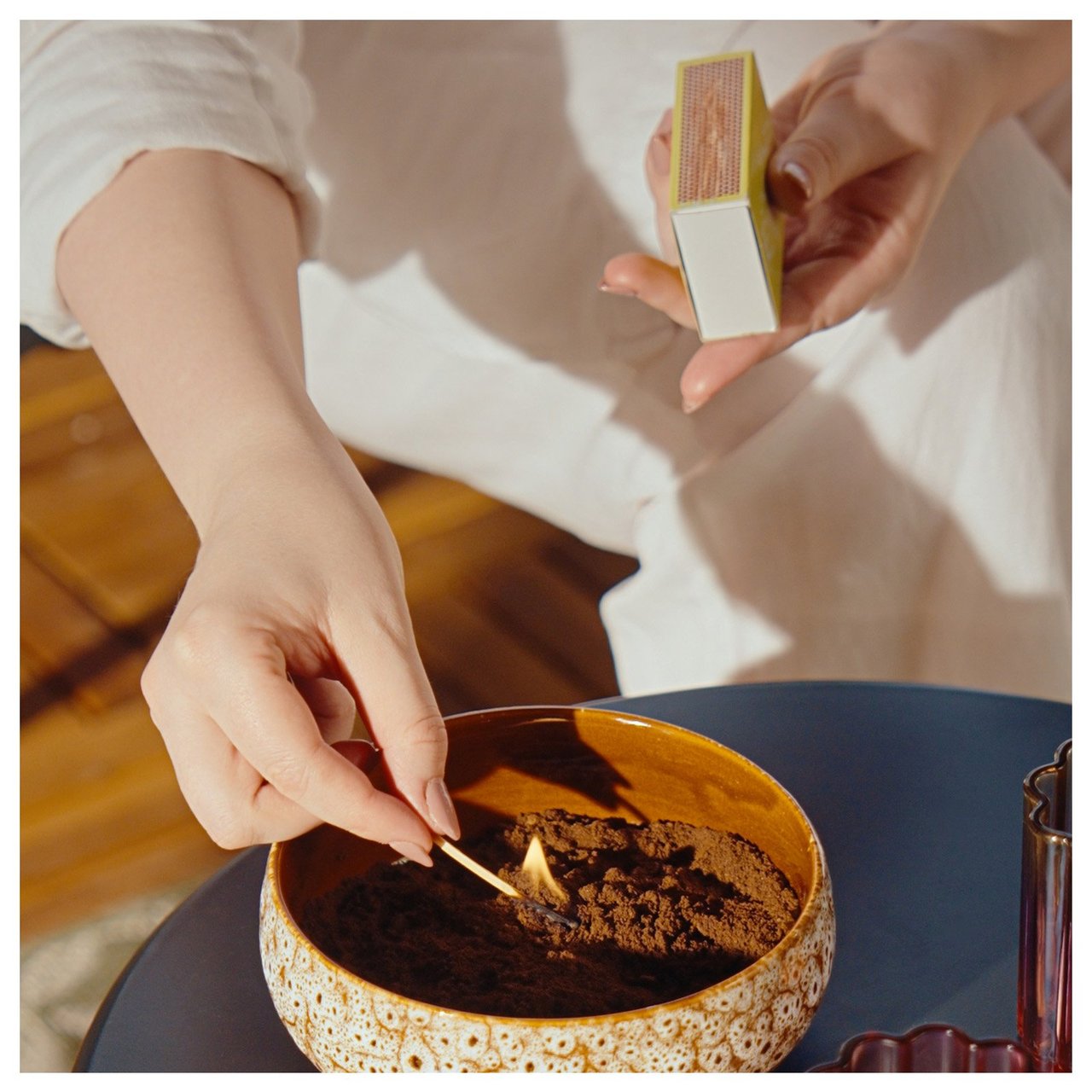 En person tenner på tørket kaffegrut i en ildfast skål for å holde myggen unna.