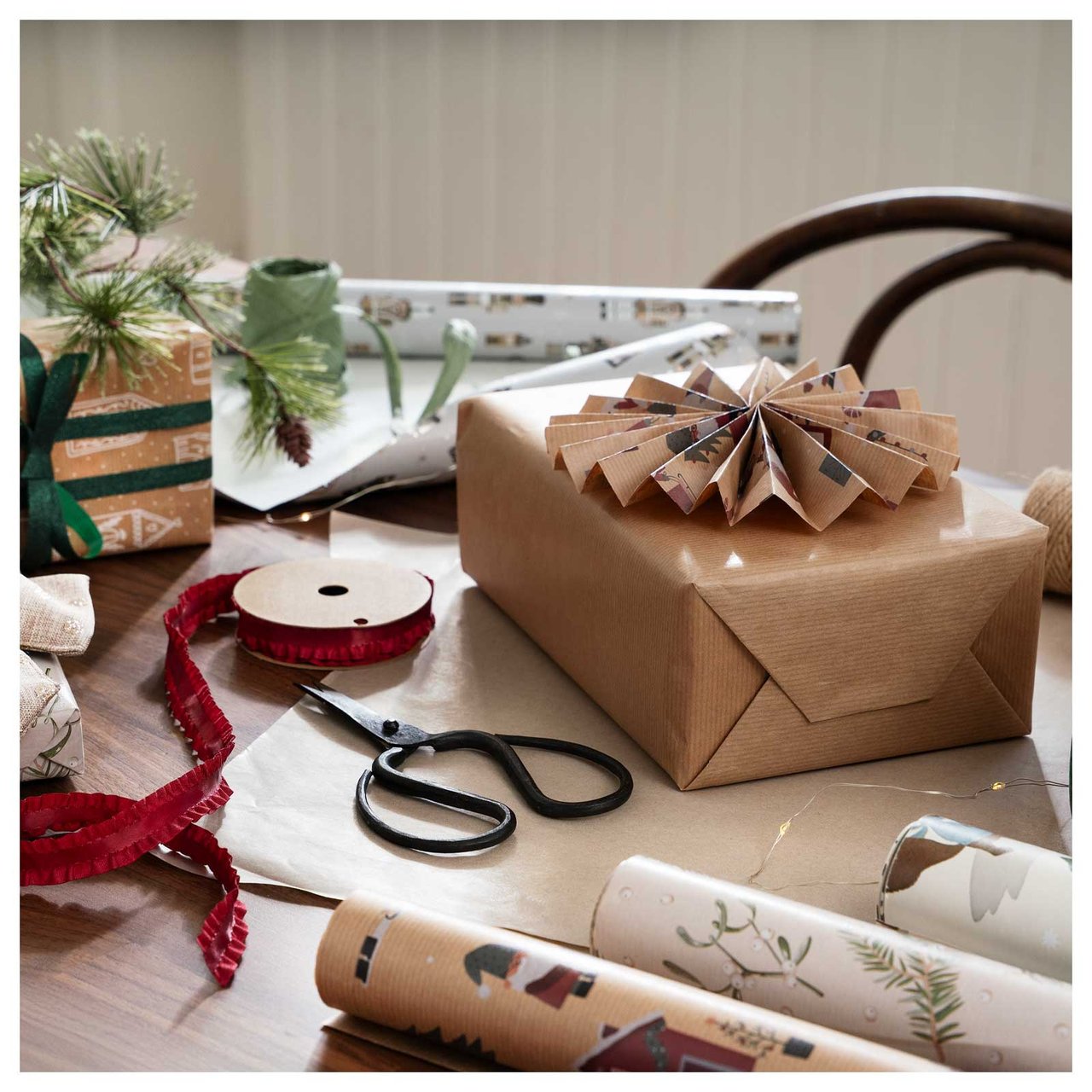 Ein Tisch mit verpackten Weihnachtsgeschenken, Geschenkpapier, Schere und Bändern.