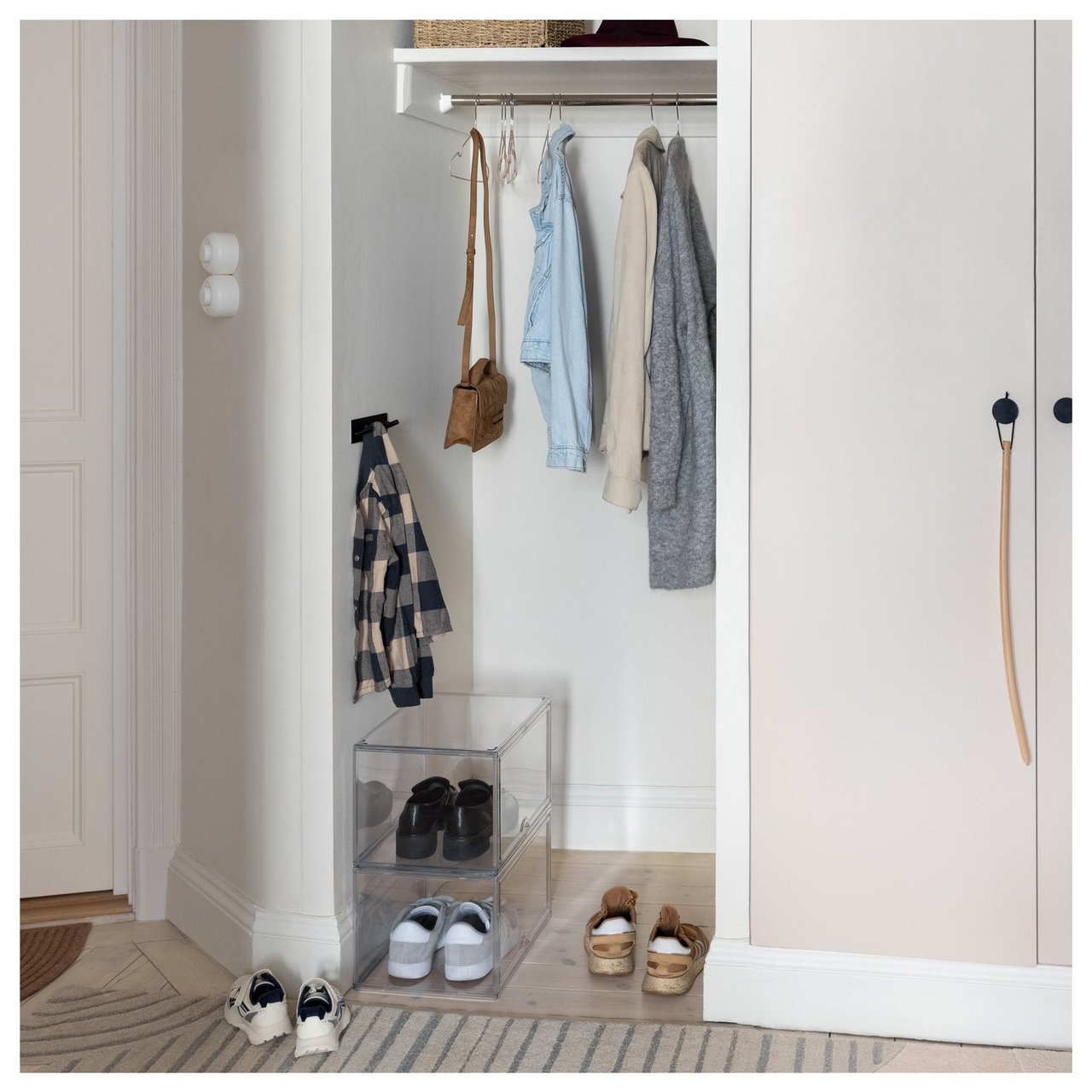 Gang med gjennomsiktige skoesker, klær på hengere og en oppbevaringskurv på en hylle.