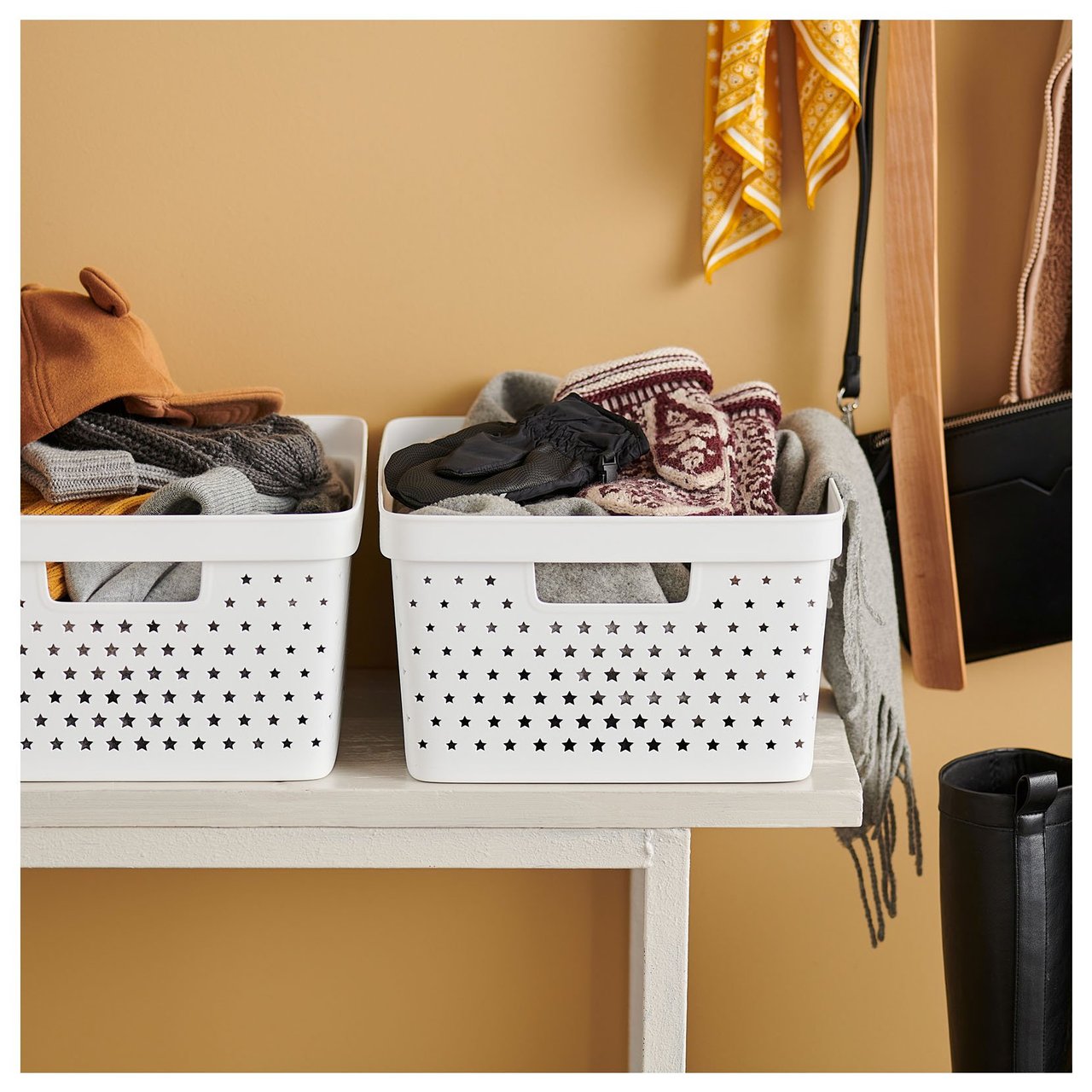 Weiße Kunststoffboxen auf einer Sitzbank in einem Flur mit orangefarbener Wand.