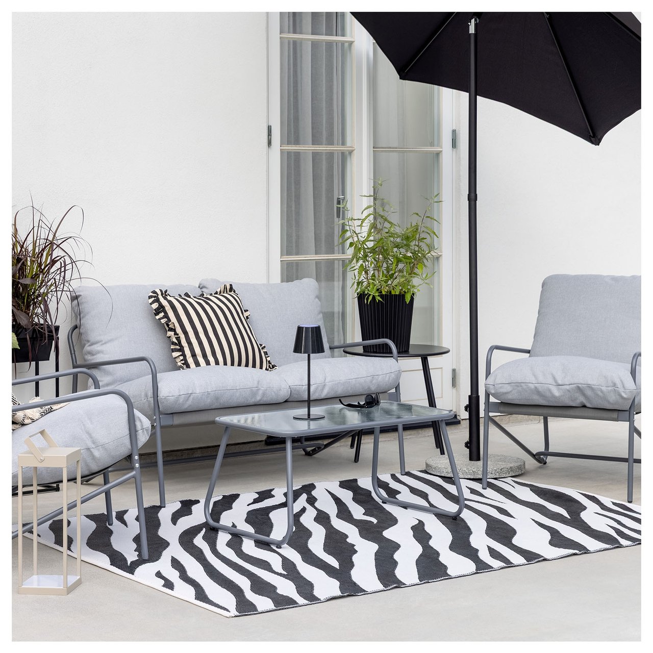 Uteplass med grå loungegruppe på et sebramønstret teppe.