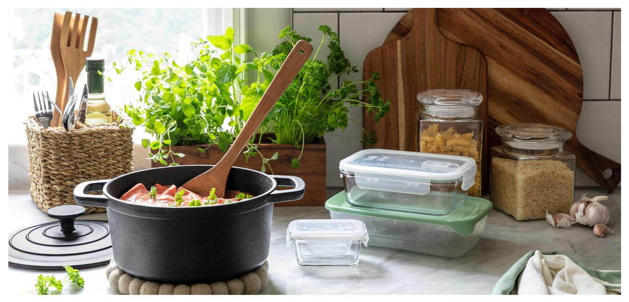 Köksbänk med gryta, matlådor, örter och redskap i ett uppdukat och inspirerande matlagningssammanhang.