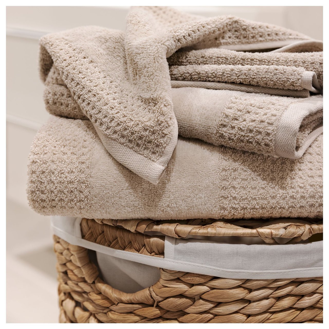 Beigefarbene Handtücher mit Waffelstruktur auf einem Wäschekorb.