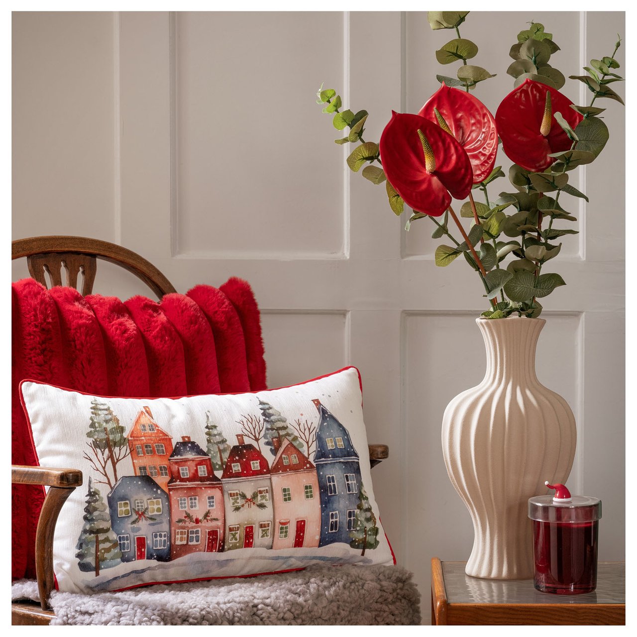 Sisustettu nurkkaus tyynyllä, viltillä ja kukkamaljakolla luo kodikkaan joulutunnelman.