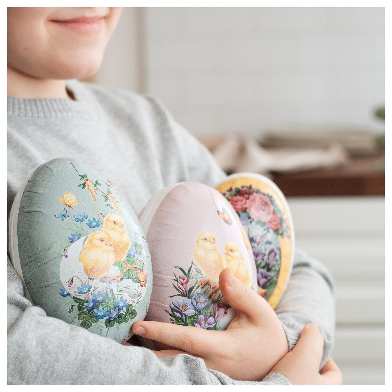 Kinder mit drei bunten Ostereiern im Arm.