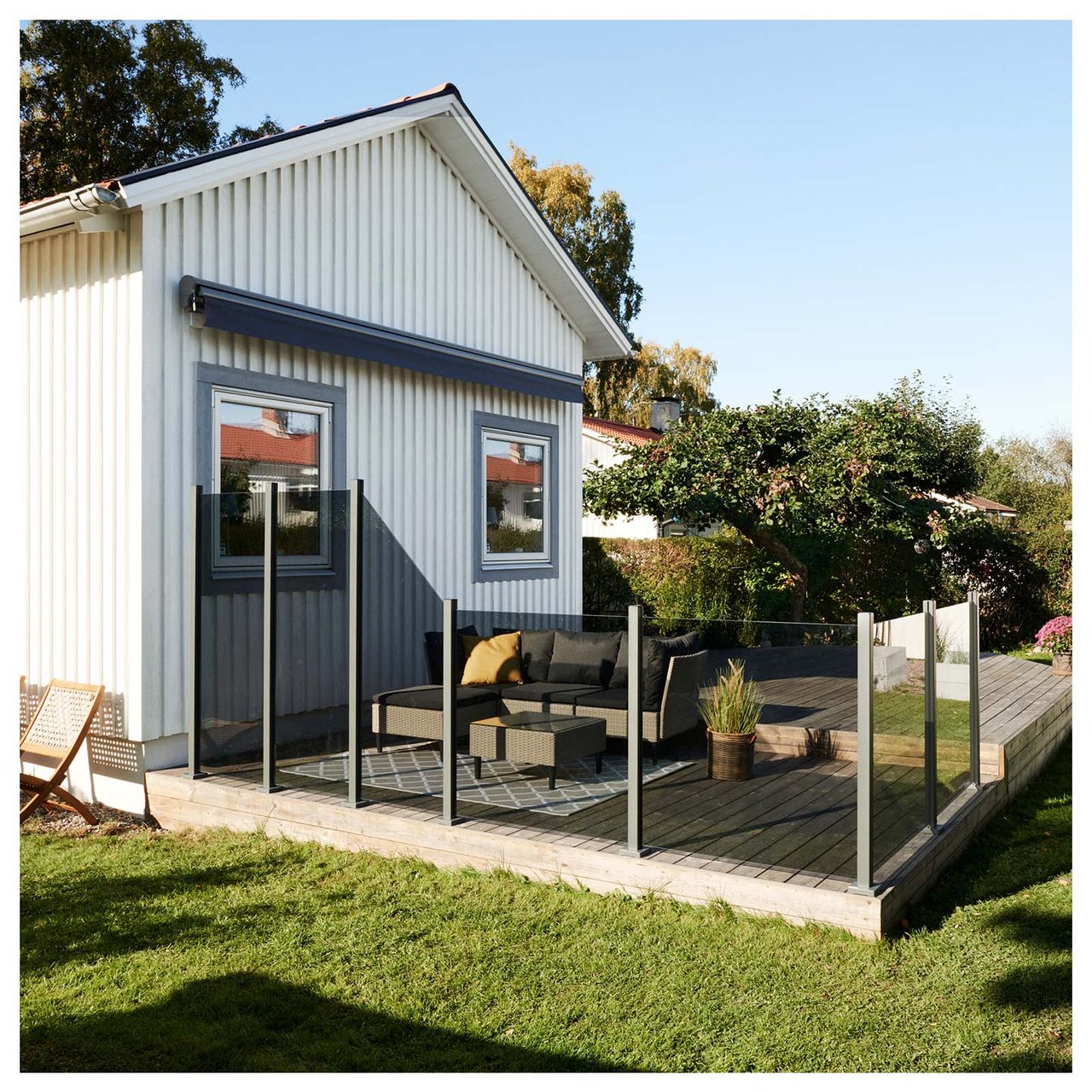 Vit villa med stor altan inramad av tonade glasräcken.