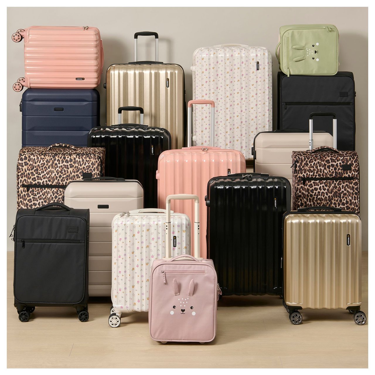 Useita erilaisia matkalaukkuja asetettuna beigen väristä seinää vasten inspiroivassa ympäristössä.