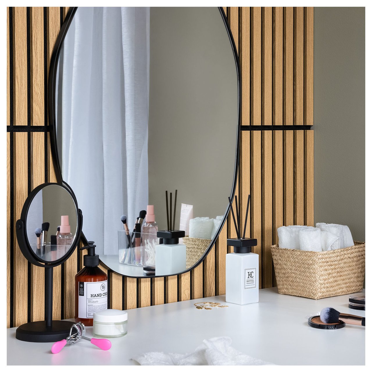 Sminkhörna med akustikpanel på väggen bakom bordet. En spegel i organisk form har monterats på panelen.