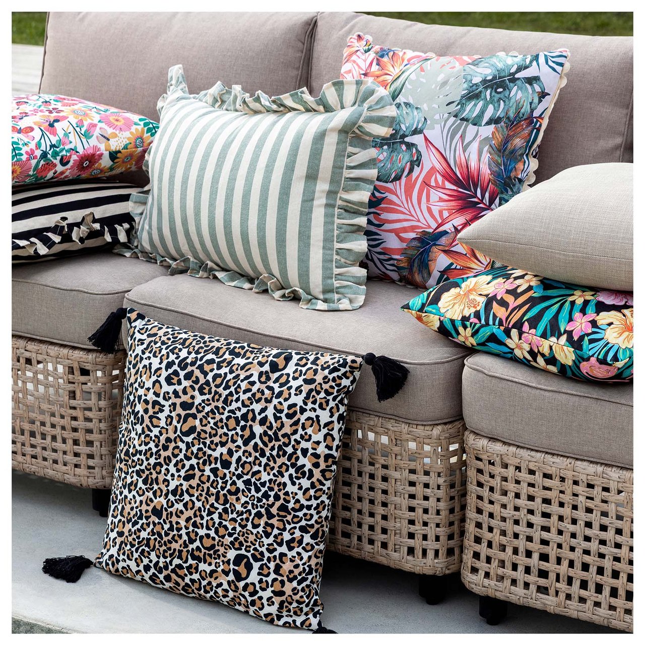 En beige loungesofa fylt med puter i forskjellige farger og mønstre.