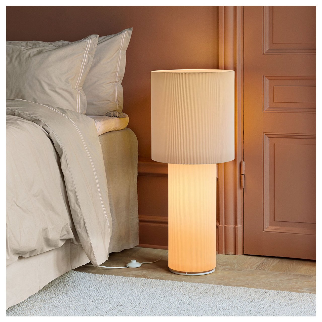 En beige golvlampa intill en säng.