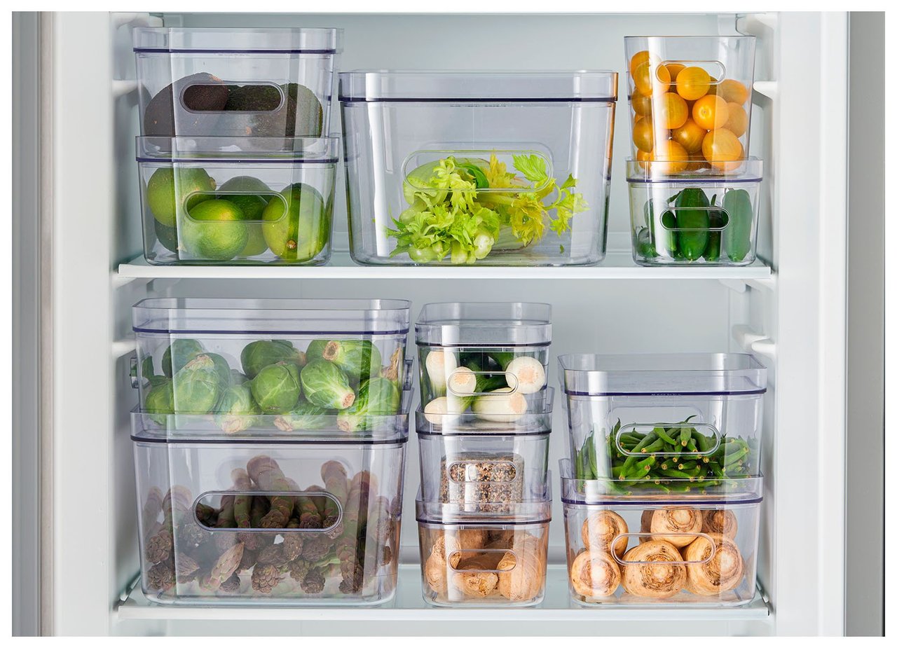 Öppet kylskåp med transparenta förvaringslådor i plast fyllda med frukt och grönsaker.