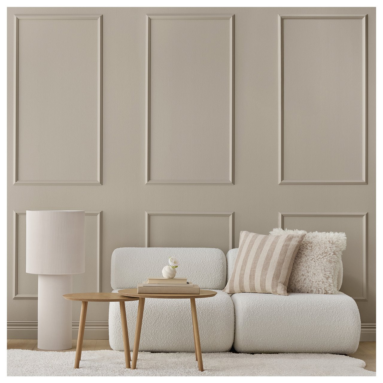 Ett vardagsrum med en grå-beige vägg med rutor av dekorlister.