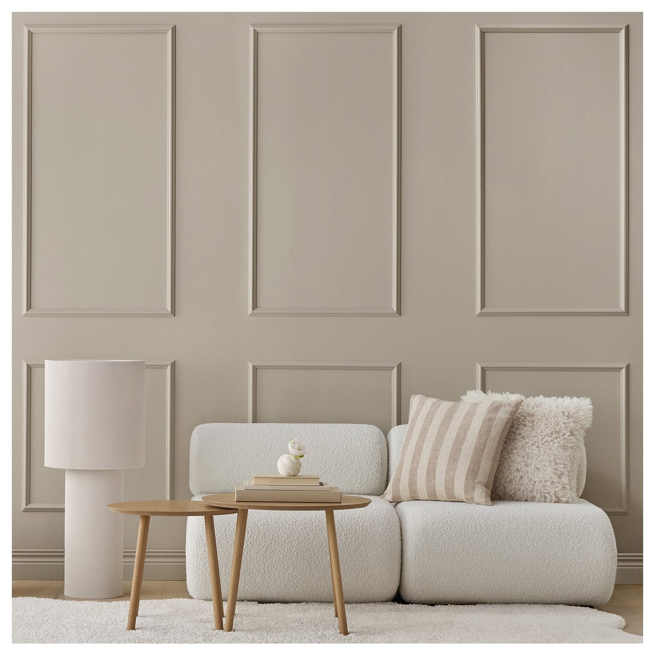 Ett vardagsrum med en grå-beige vägg med rutor av dekorlister.