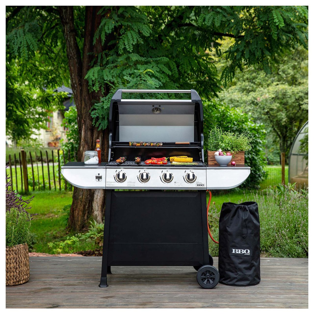 Gasolgrillen Evolution i en trädgård. På grillgallret ligger grönsaker.