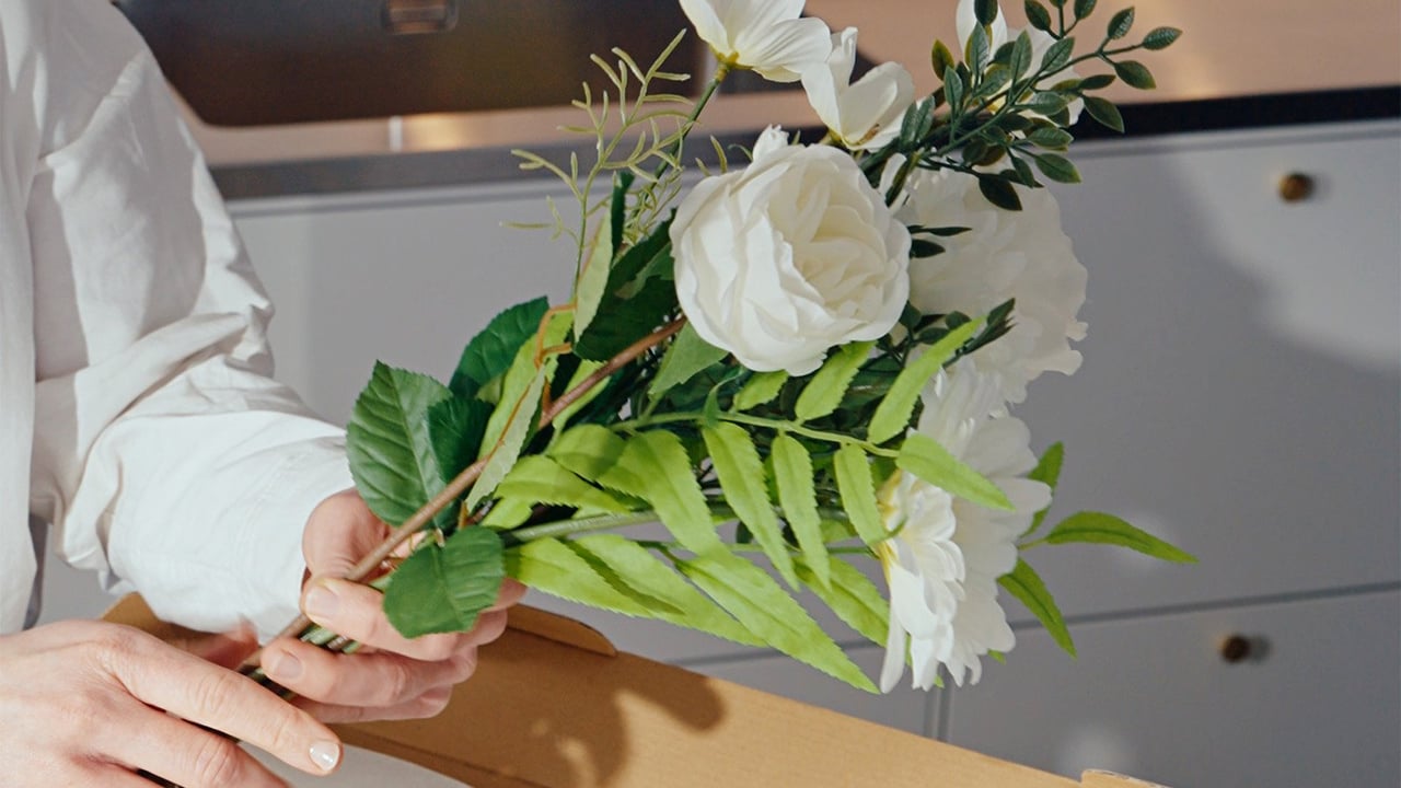 Person sätter ihop en bukett med konstblommor.