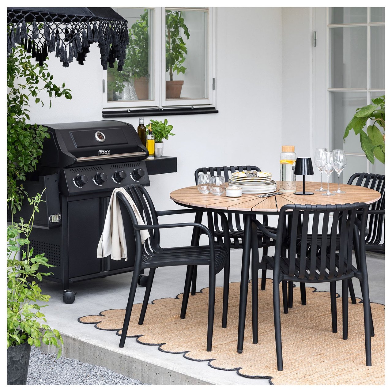 Sieben Personen essen im Freien in einem Garten zu Abend, der mit in der Dunkelheit leuchtenden Solarlichterketten geschmückt ist.