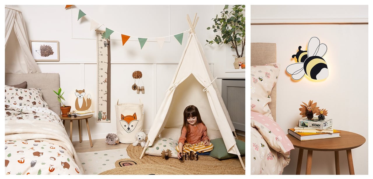 Kinderzimmer in natürlichen Farben. Bett mit Baldachin und Kind, das im Tipi spielt. Lampe mit Hummelmotiv über dem Nachttisch.
