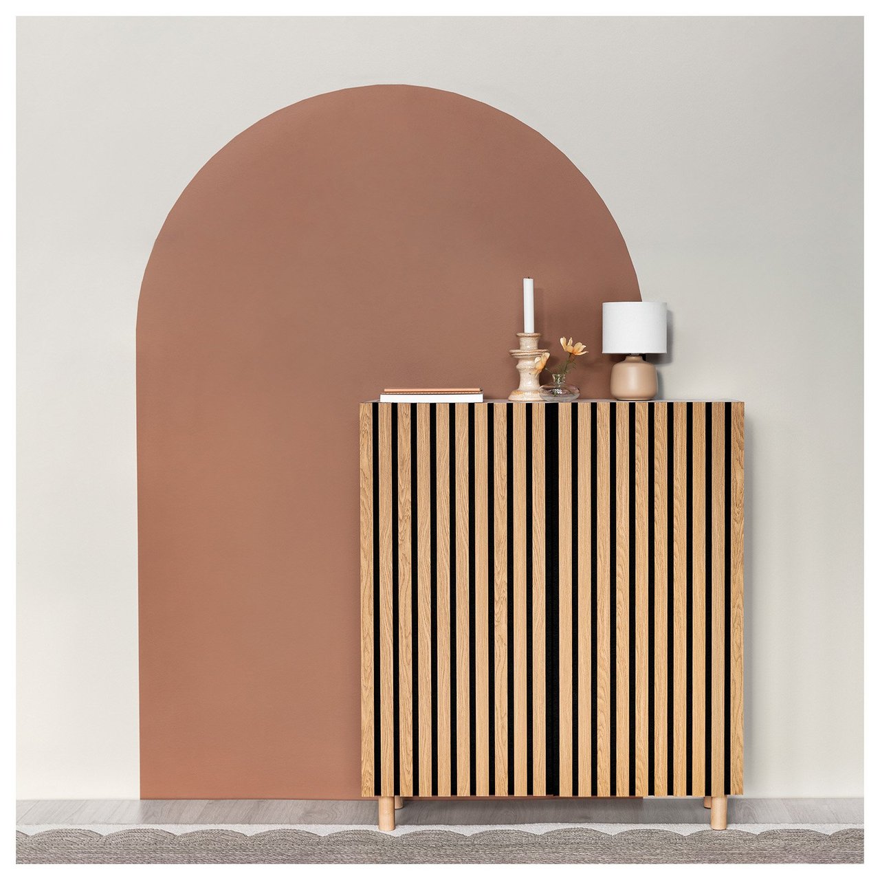 Skåp täckt med akustikpanel. I bakgrunden är en portal målad i rödbrunt på väggen.