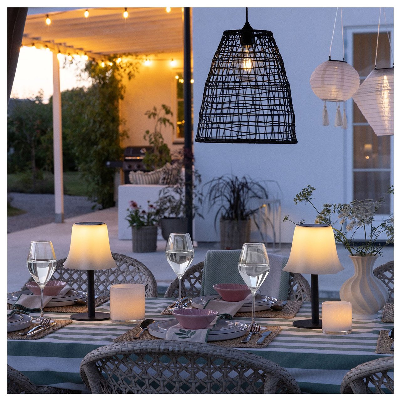 Et dekket bord med bordlamper omgitt av hengende lamper og lysslynger.