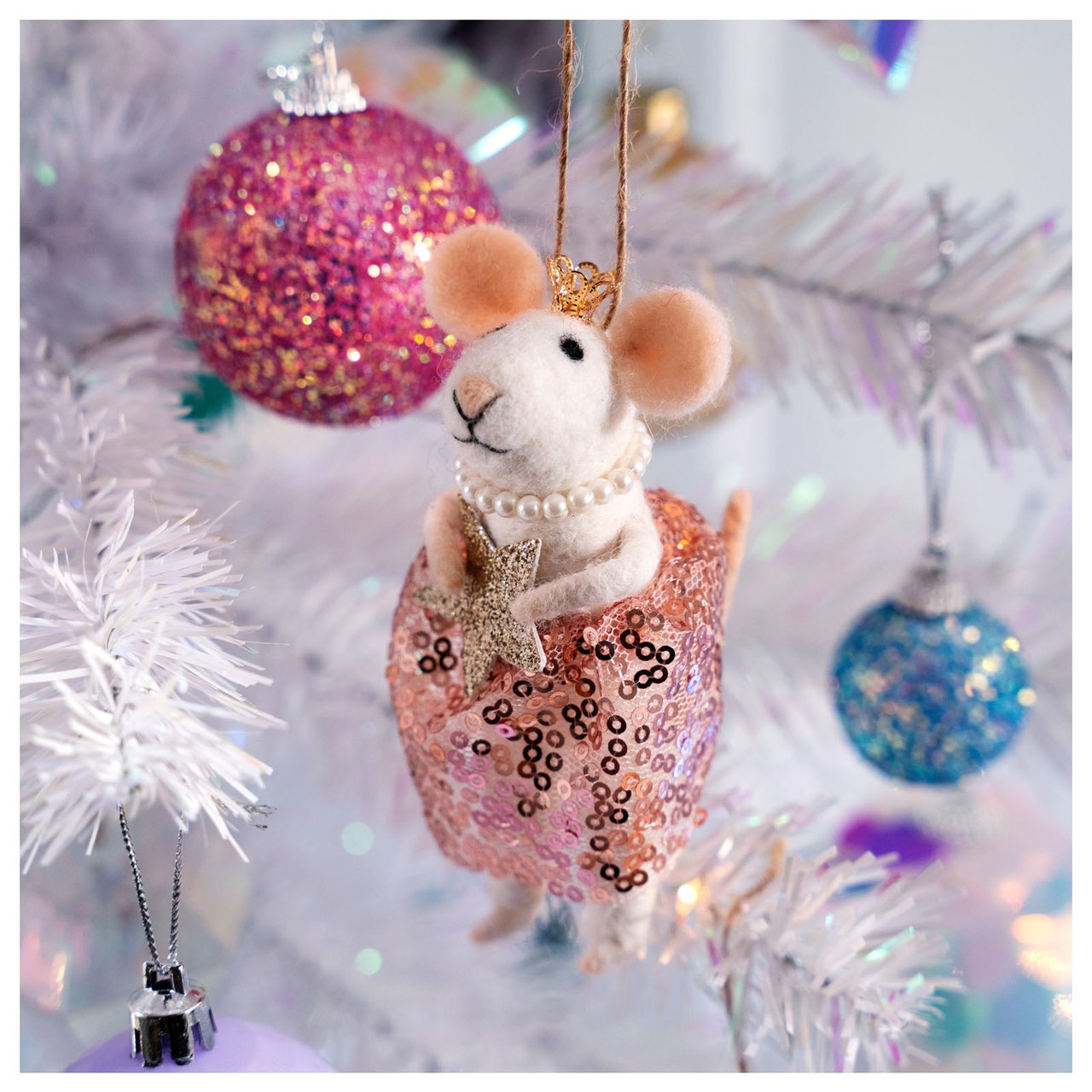 Eine Maus mit rosa Rock hängt neben einer rosa Kugel.