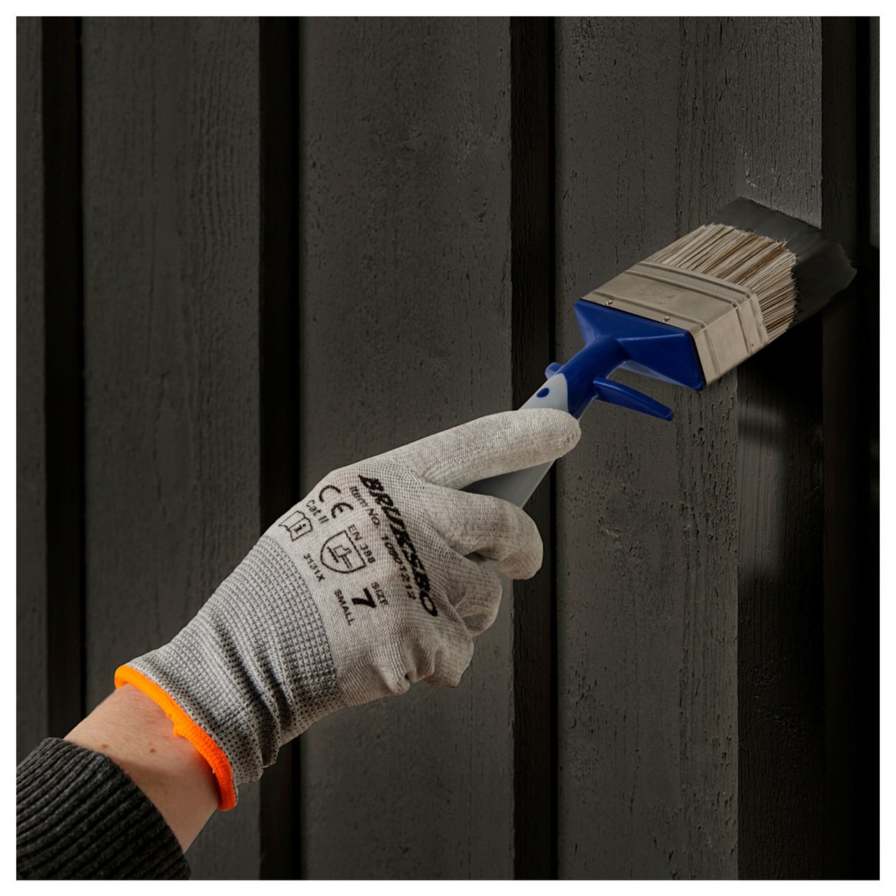 Valkoista julkisivua maalataan telalla, jossa on punainen jatkovarsi.