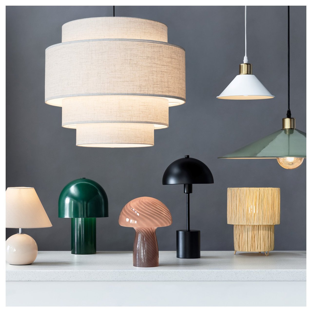 Erilaisia katto- ja pöytävalaisimia aseteltuna harmaata seinää vasten inspiroivassa ympäristössä.