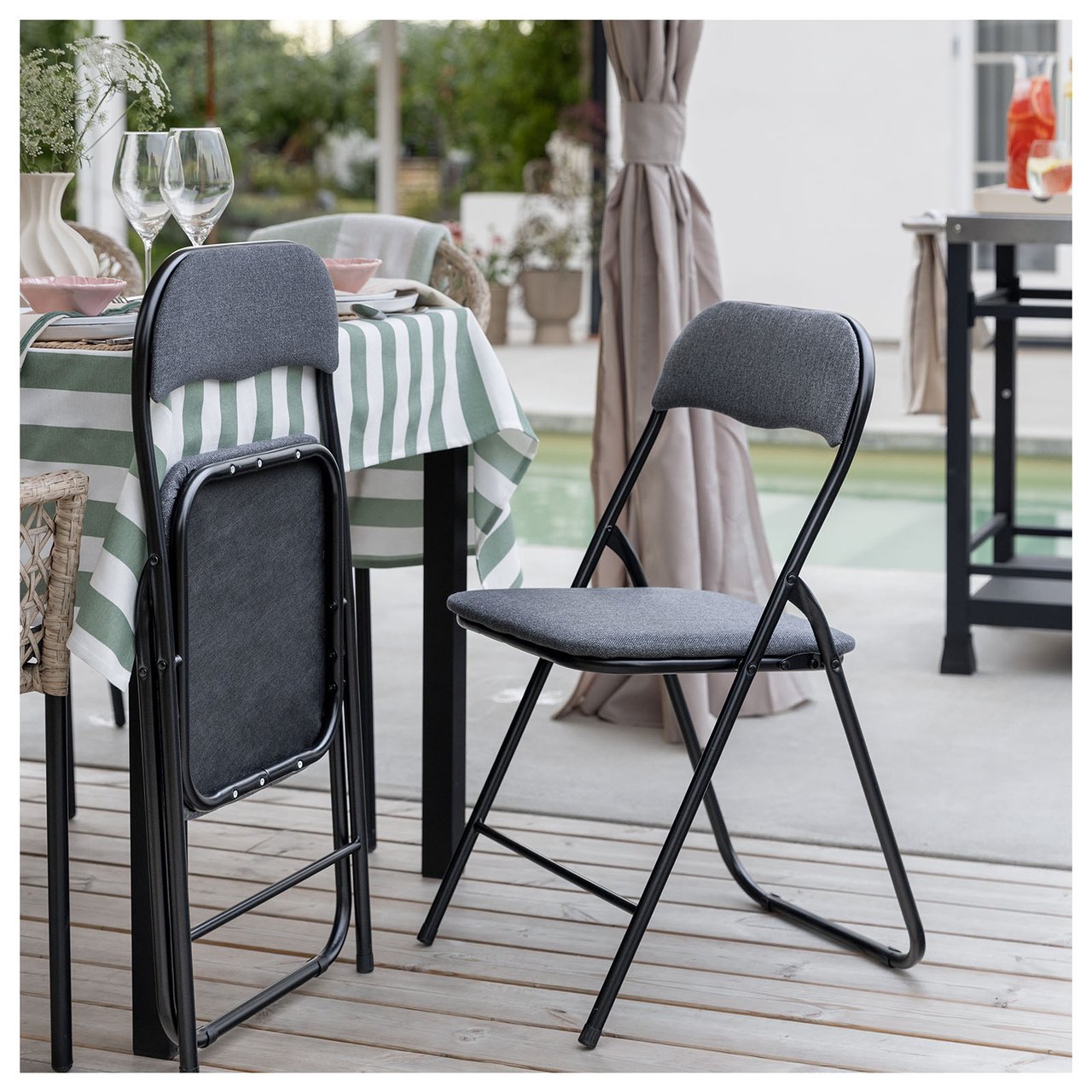Svarta klappstolar vid ett bord på en uteplats.