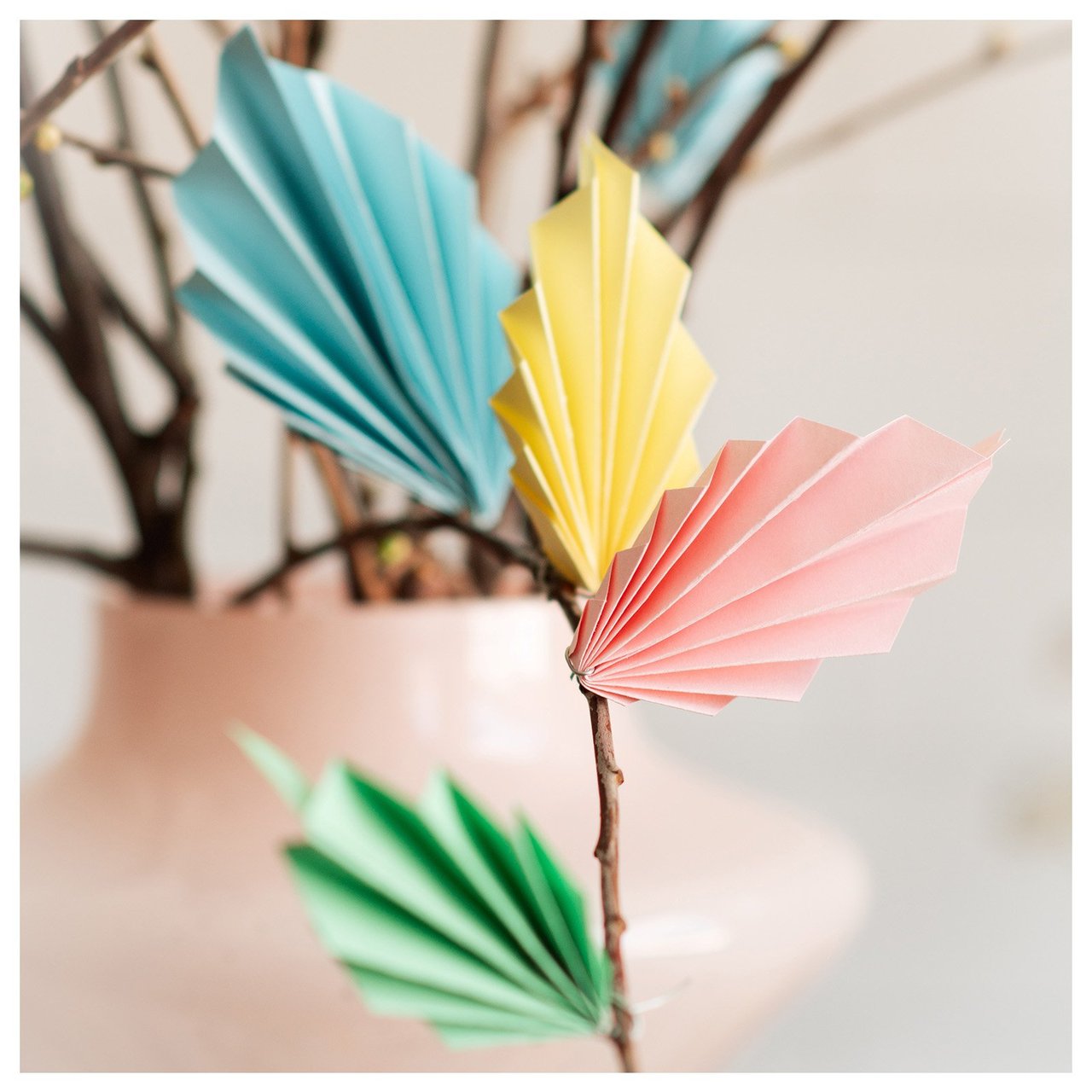 Osterzweige in Nahaufnahme, dekoriert mit bunten Federn aus Papier.