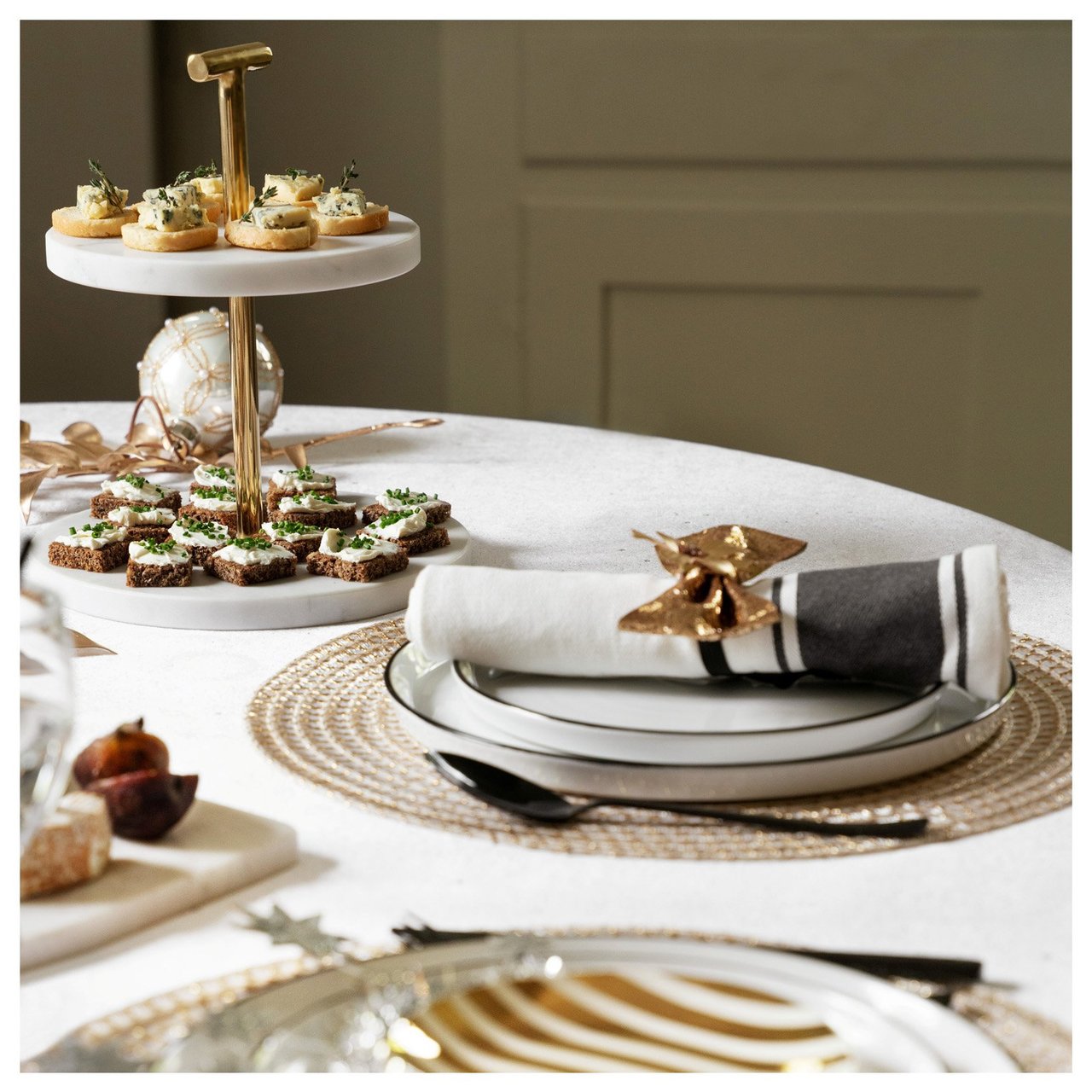 Nyårsdukning i vitt och guld med randig tallrik, stjärndekor och glittrande detaljer.