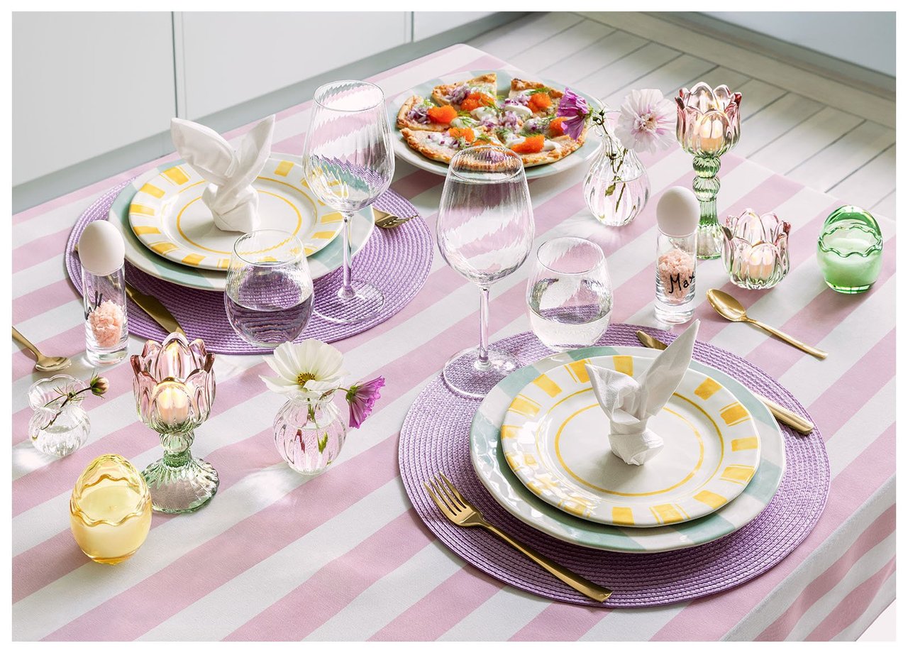 Tisch mit Osterdekoration in Rosa, Lila und Gelb.