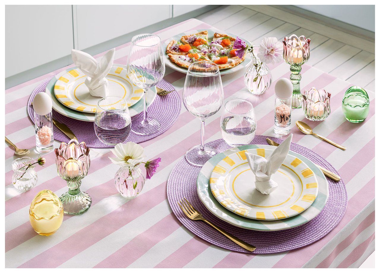 Tisch mit Osterdekoration in Rosa, Lila und Gelb.