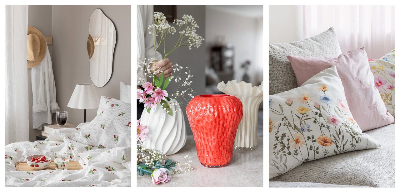 Säng med jordgubbsmönstrade sängkläder. Jordgubbsformad vas med blommor. Blommiga kuddar i en soffa.