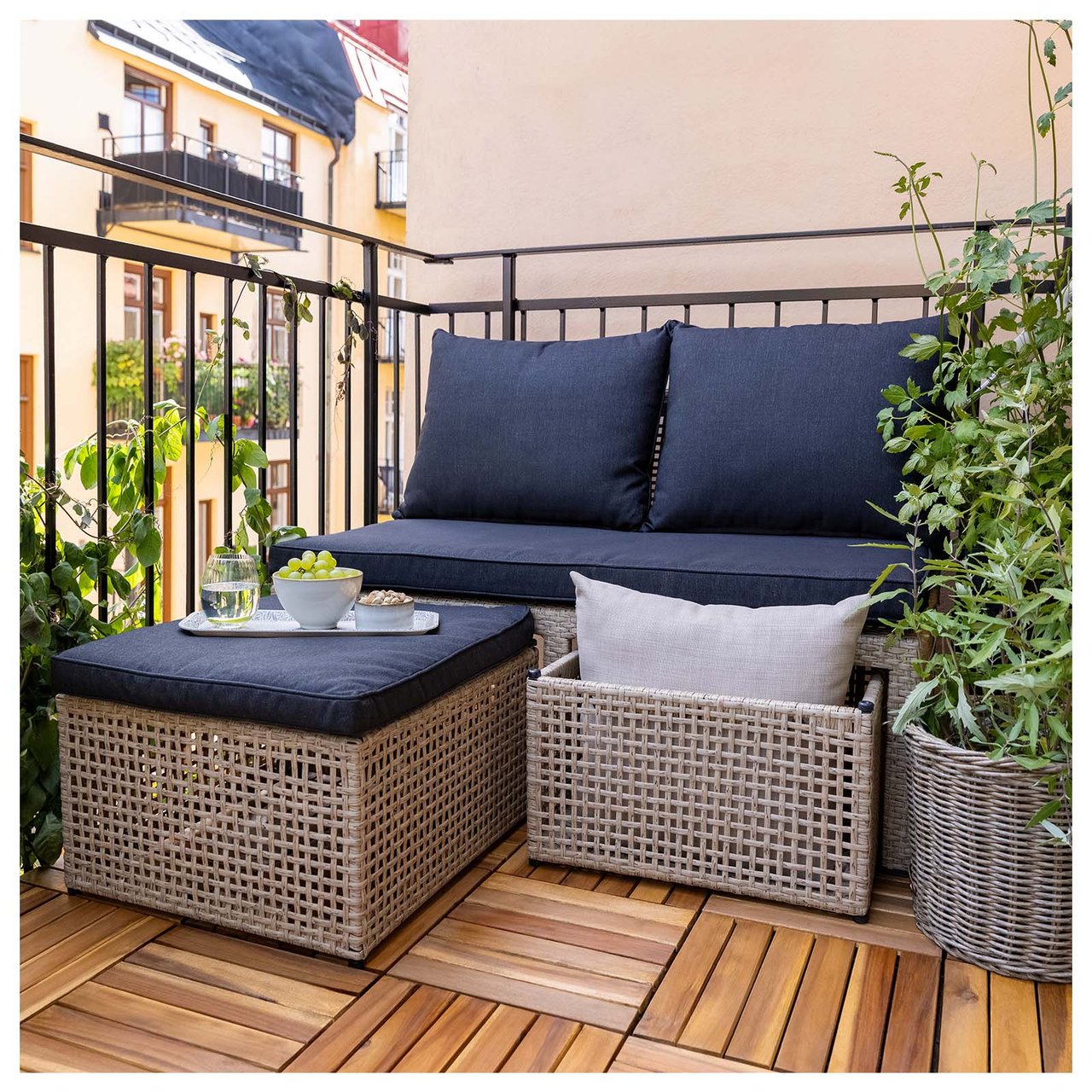 En beige toseters sofa i rotting på en balkong. Sofaen har to oppbevaringsbokser.