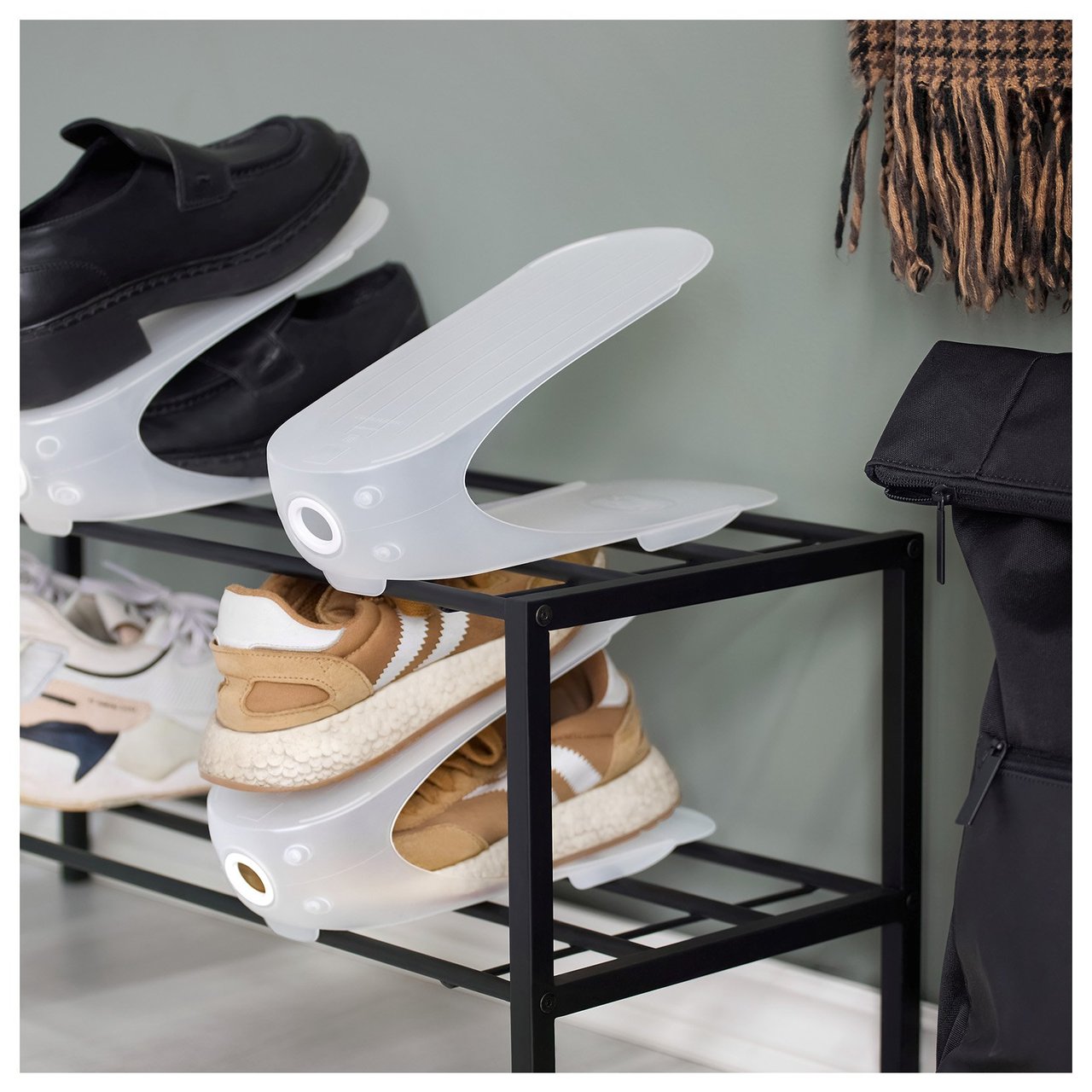 Schuhhalter aus Kunststoff, die auf einem Schuhregal in einem grün gestrichenen Flur liegen.