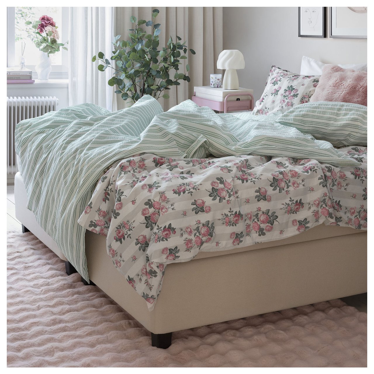 Dobbelseng med pastellfargede sengetekstiler i et lyst soverom.