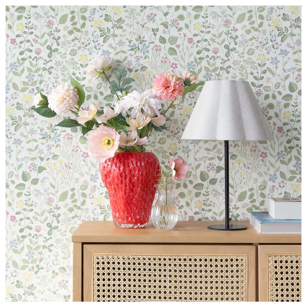 Rote erdbeerförmige Vase mit einem Strauß aus Kunstblumen in Rosa und Weiß.